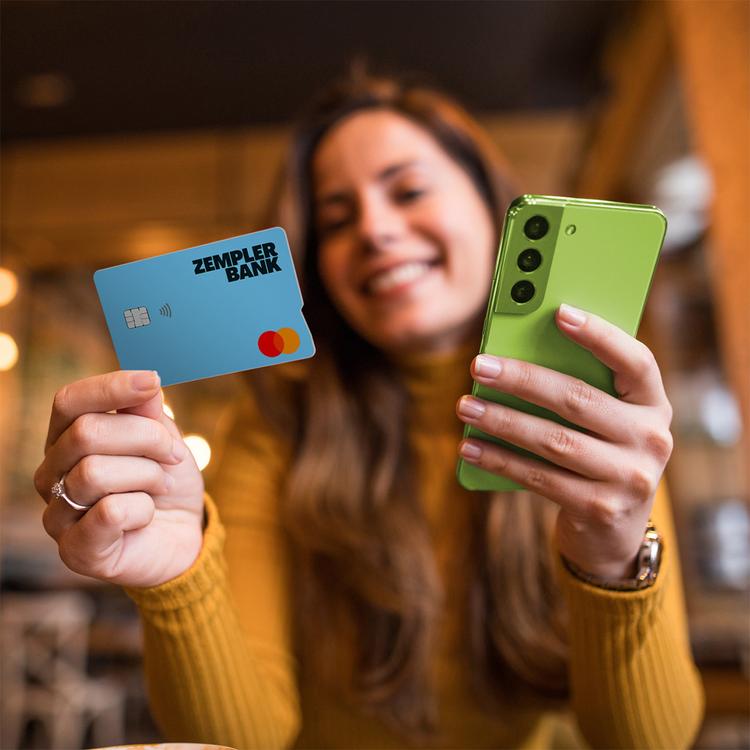 Woman looking at Zempler Bank card whilst holding mobile phone