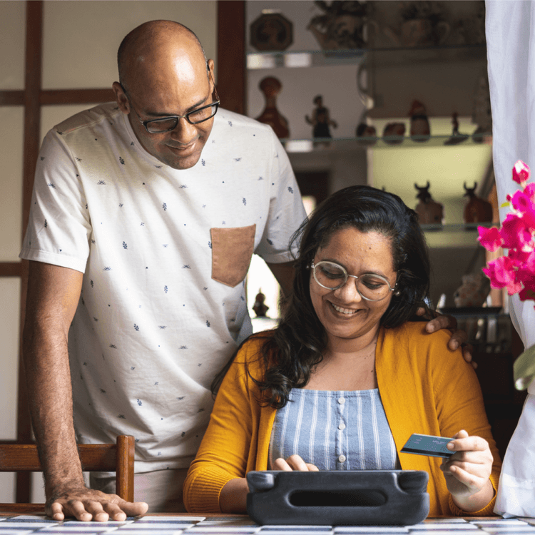 A man and a woman at a table, whilst the woman is holding a bank card