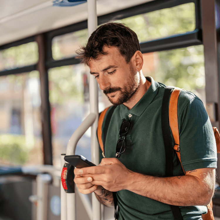 A man standing on a bus, whilst on his mobile phone
