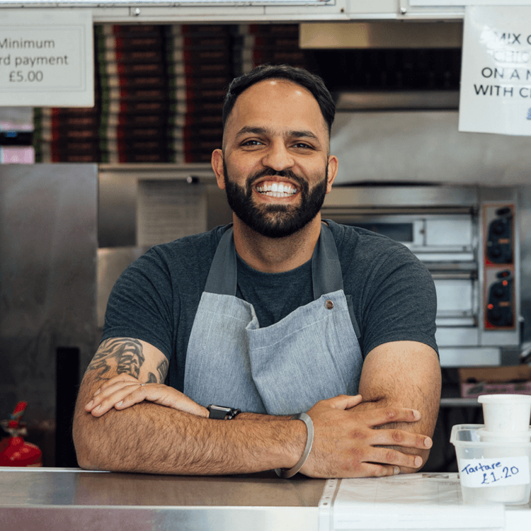 A man standing at a counter with an apron round his neck